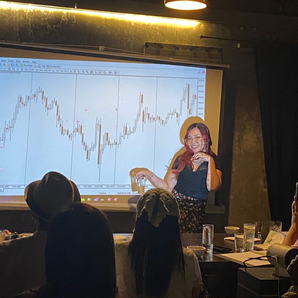 Nikki teaching a live forex class in front of a projected price chart